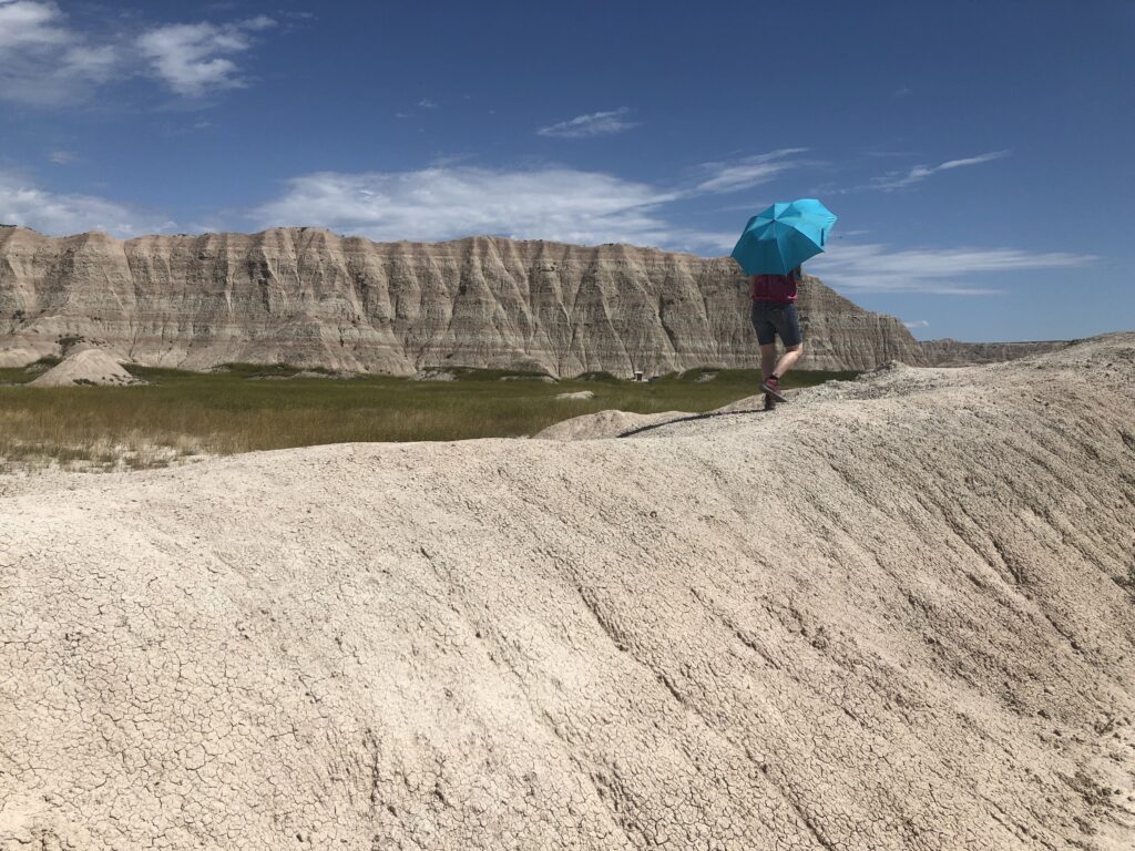 woman walking in the badlands with umbrella